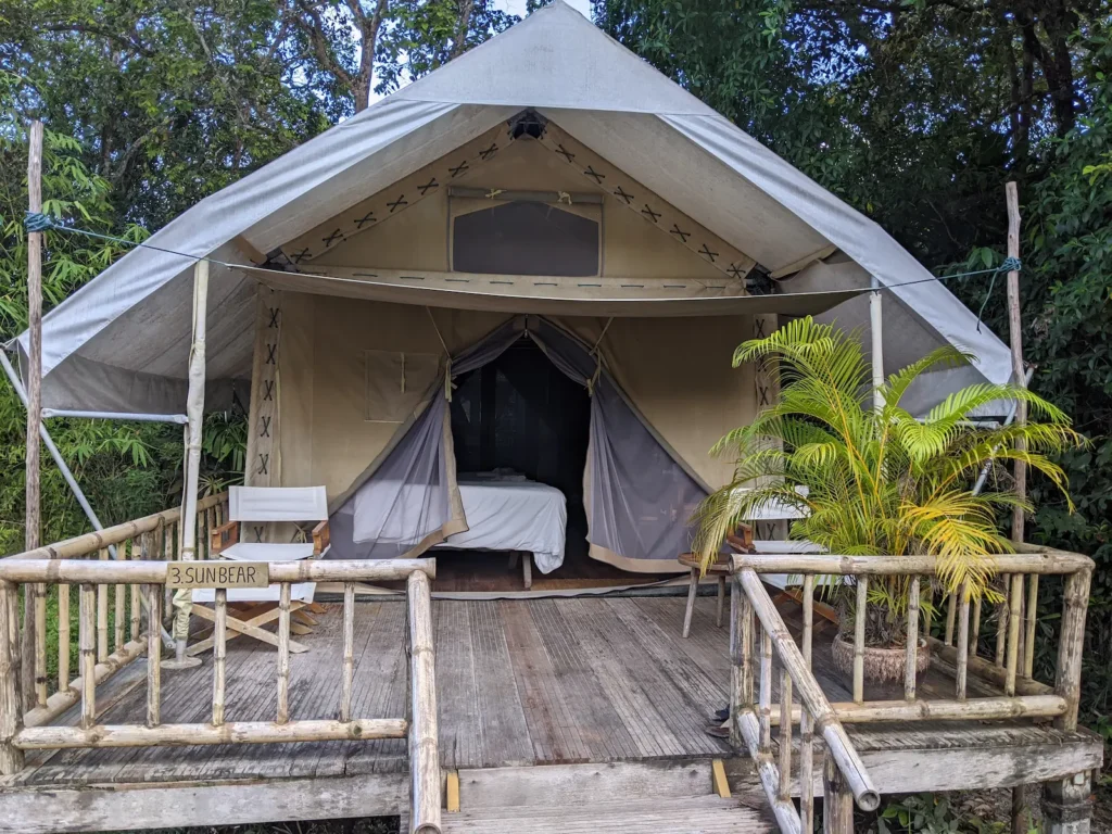 Glamping tent with a bamboo balcony and a white canvas top at Cardamom Tented Camp