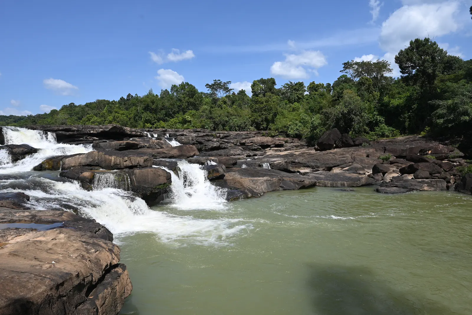 Large boulders in the Tatai river with a small waterfall cascading over them.