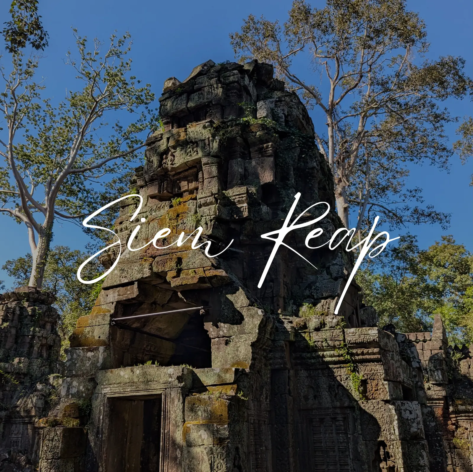 Ancient stone gateway on the eastern side of Angkor Wat with faces in the stones at the top. Text overlay says Siem Reap.