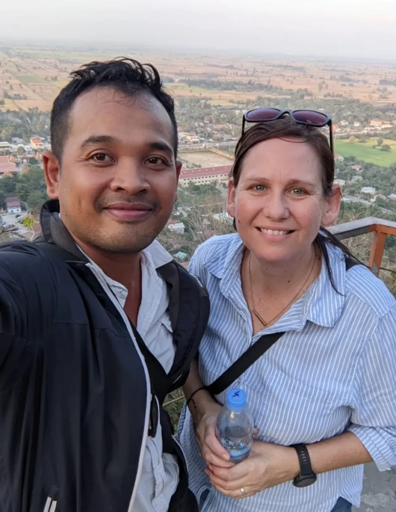 Selfie of Nehru and Mel at Phnom Sampov near Battambang with rice fields stretching across the landscape behind them.