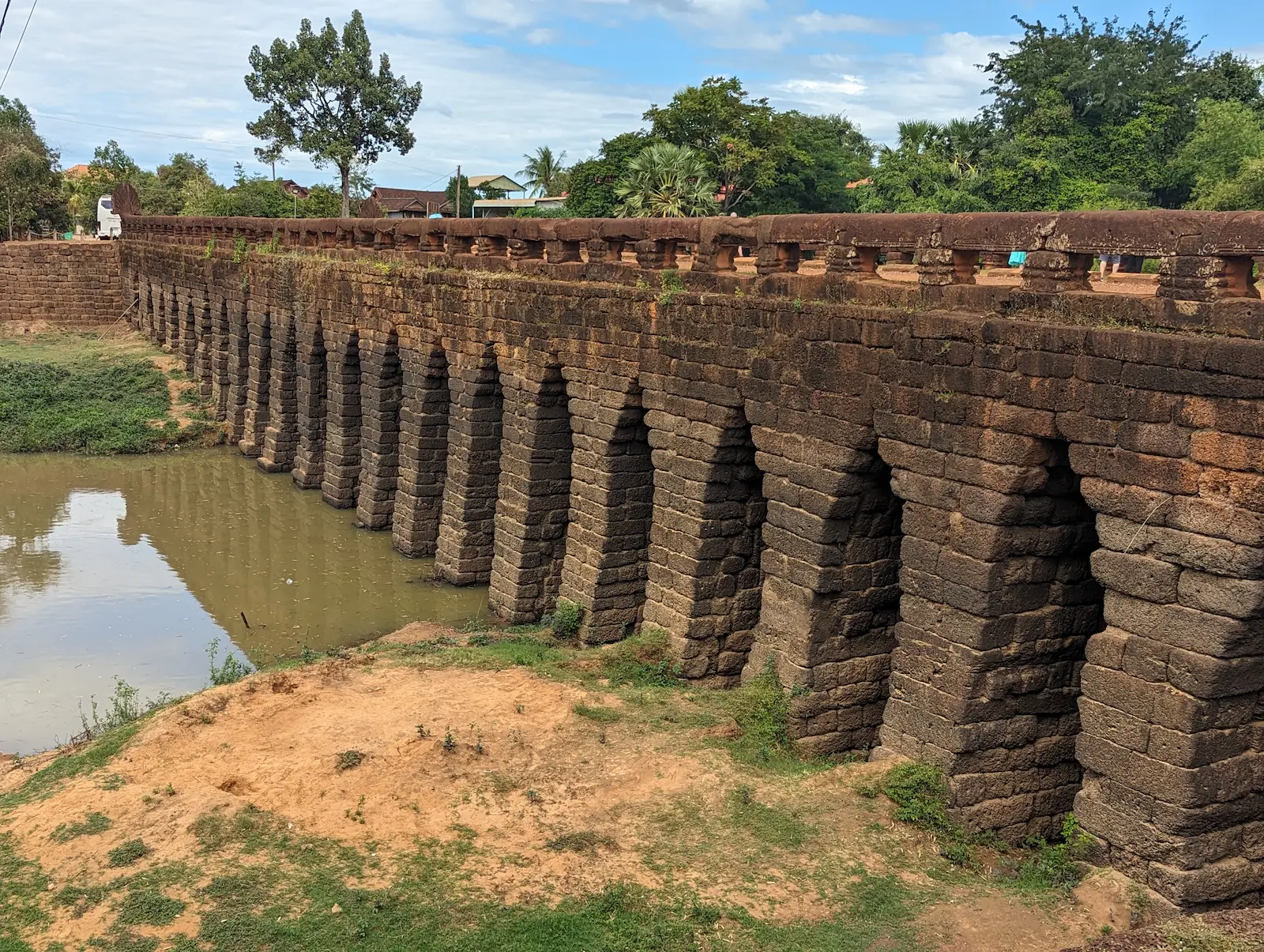 Ancient stone bridge with corbeled archways and a small river flowing through them.