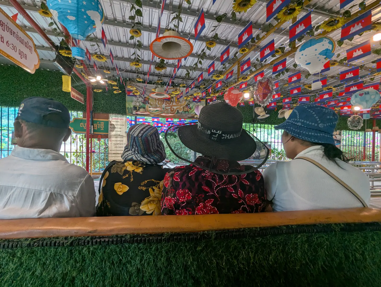Four people sit in a bamboo train under hundreds of little Cambodian flags