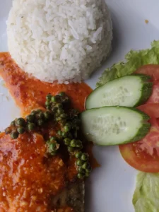 A close of shot of a plate with rice, crab in a red sauce with a green peppercorn
