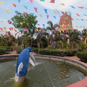 A dolphin sculpture in a pond with a large Dutch windmill in the background