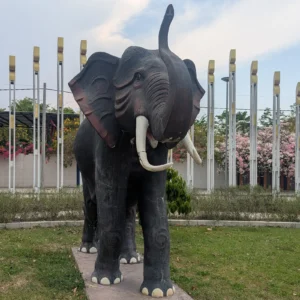A grey life sized elephant sculpture in a garden