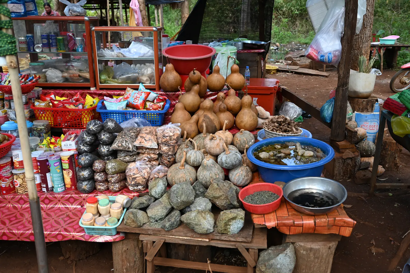 A roadside stall with layers of gords, jars and baskets of medicines.