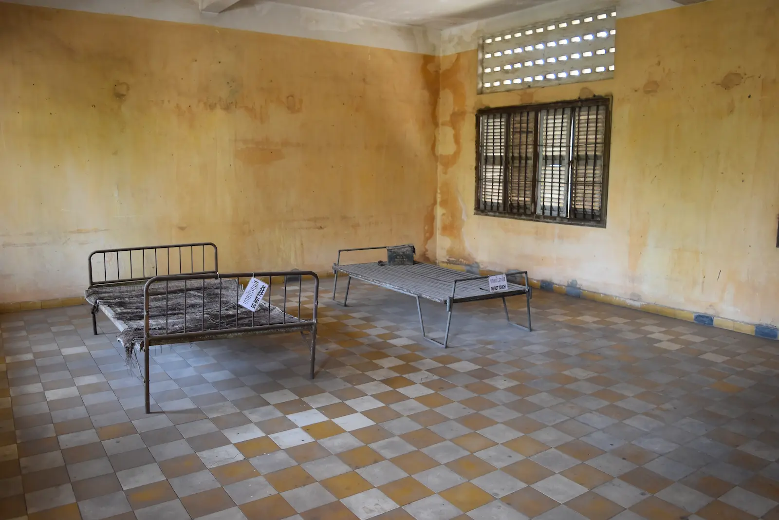 A Tuol Sleng torture room is an empty room with tiles except for two bed frames.