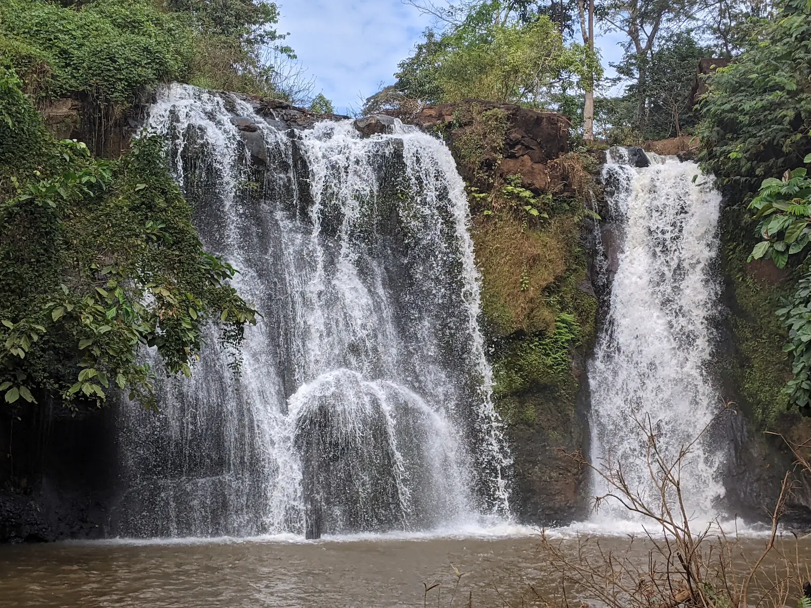A waterfall comes over a rocky ledge in two main sections.