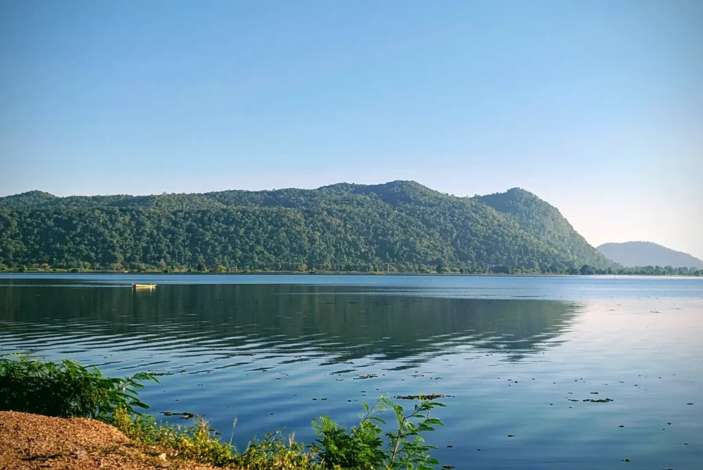 A large reservoir with blue/green water and a forested hill behind it.