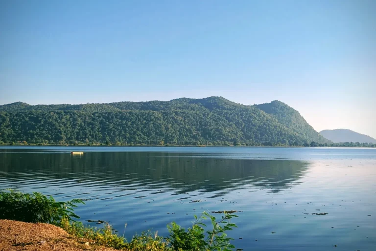 A large reservoir with blue/green water and a forested hill behind it.