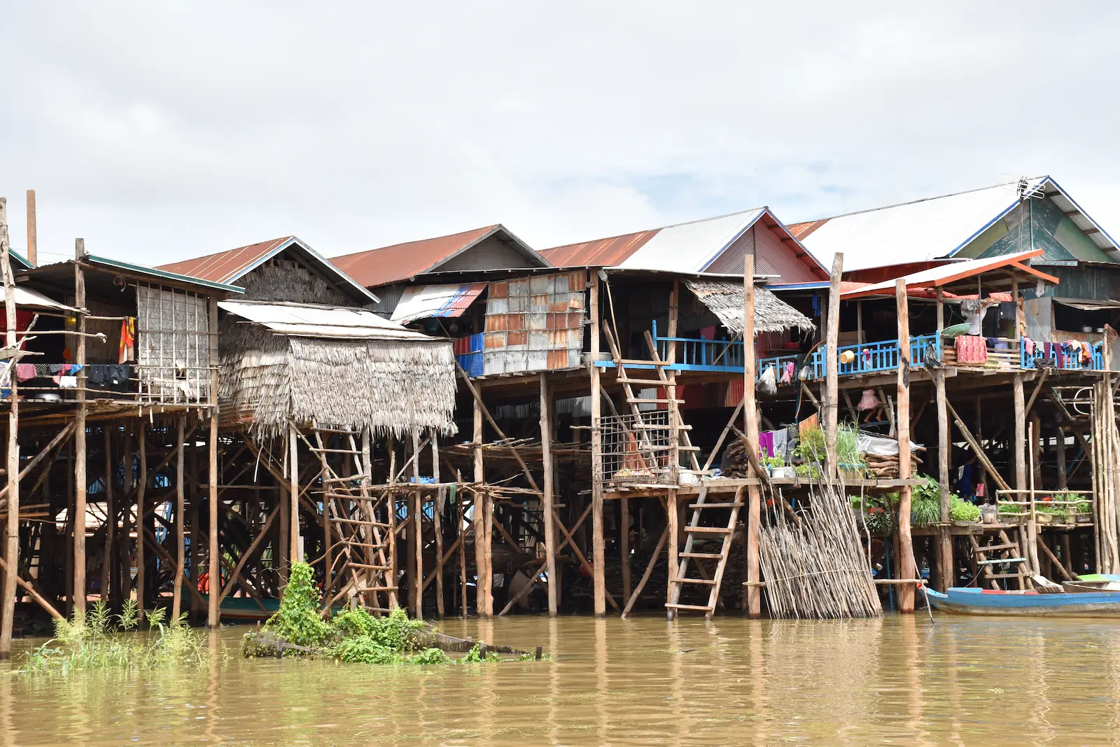 Houses on stilts in a line with the water under them.