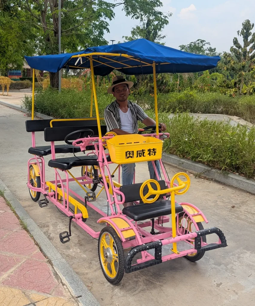 Nehru is driving a four wheeled bicycle hat looks like a tuk tuk
