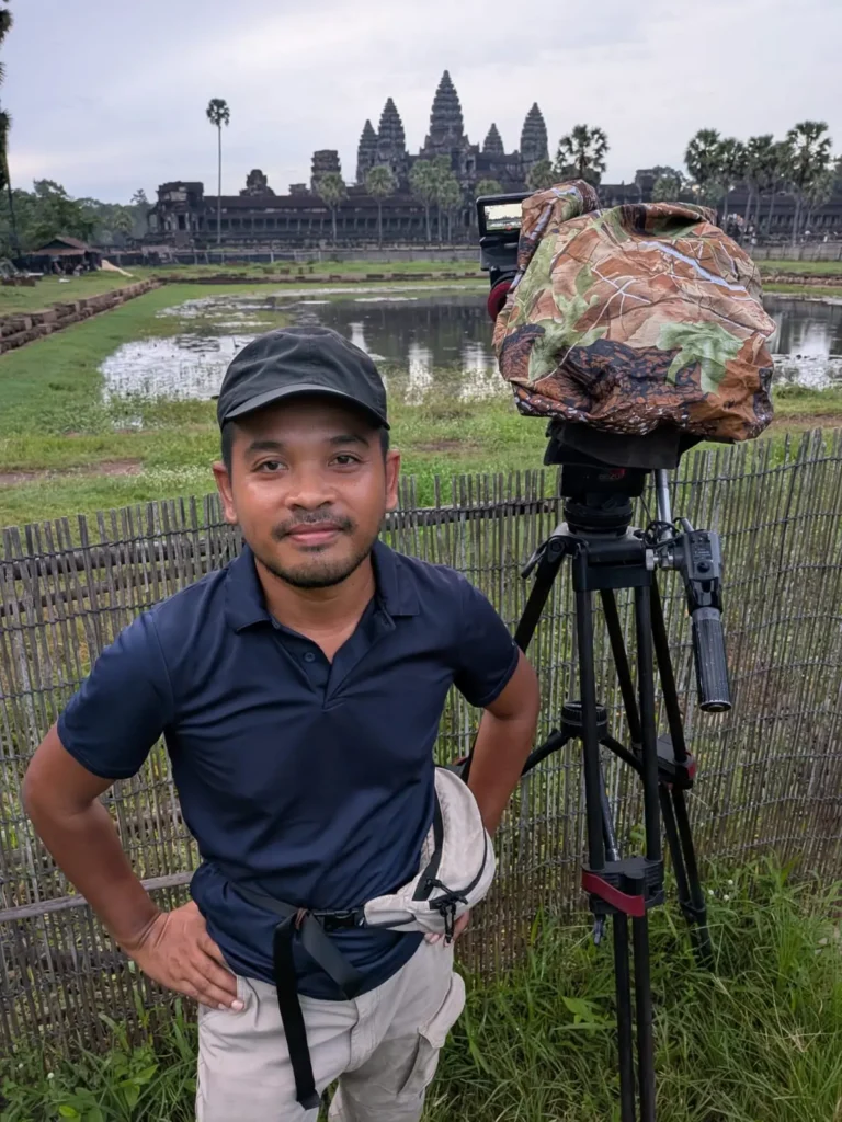 Nehru stands next to a large camera on a tripod with Angkor Wat in the background.