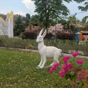 A giant rabbit stature with pink paper like flowers in the foreground