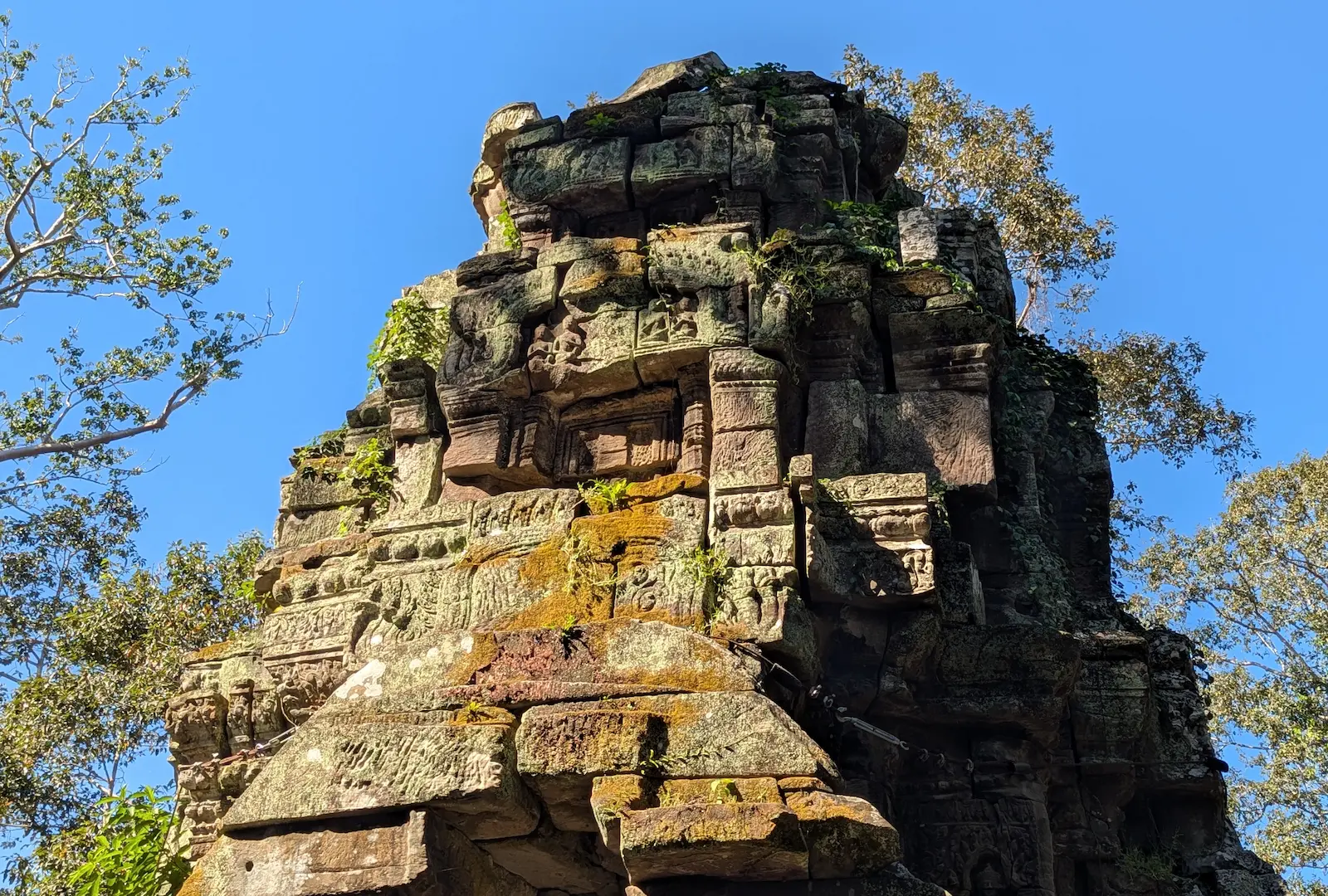 The top of an old temple with moss growing over the top of it.