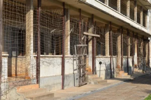 A building with columns over a verandah is covered in barbed wire.