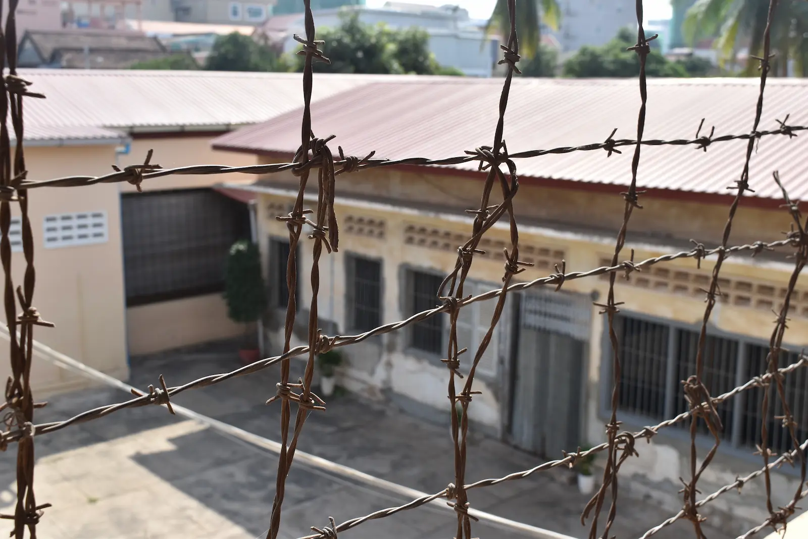 Looking through the barbed wire at a school building at S21 Prison