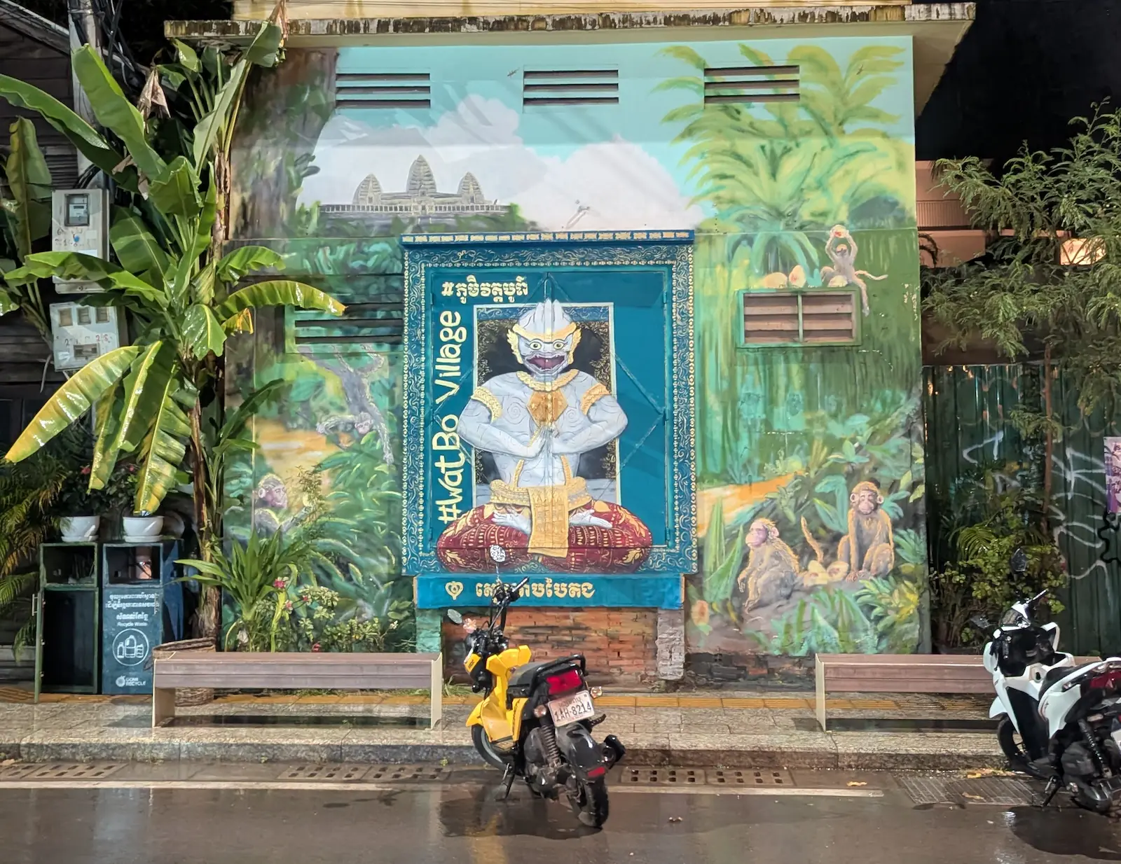A mural on a wet street of Siem Reap has a Hanuman with the words Wat Bo beneath it
