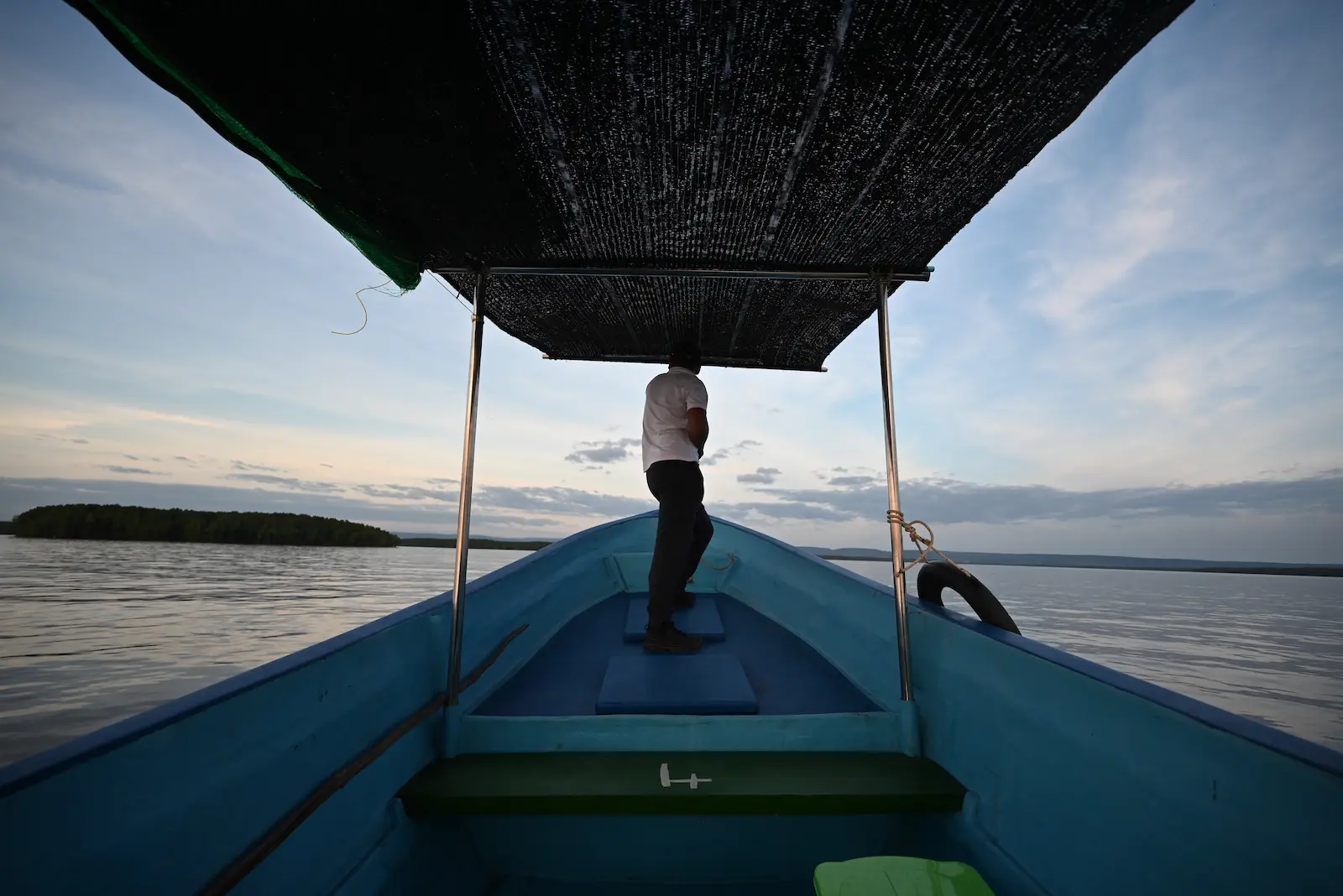 photo taken inside a blue wooden boat at sunset. Nehru stands at the front of the boat.
