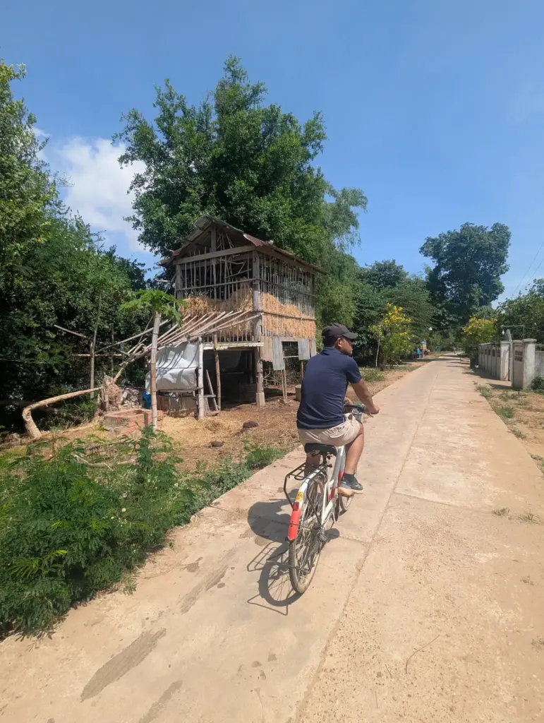Nehru cycles on a path with a hay stack next to him.