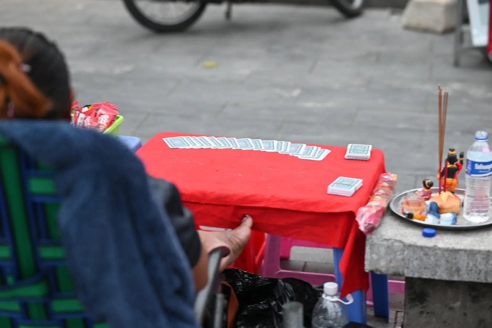 A fortune teller sits at a table with cards laid out on it.