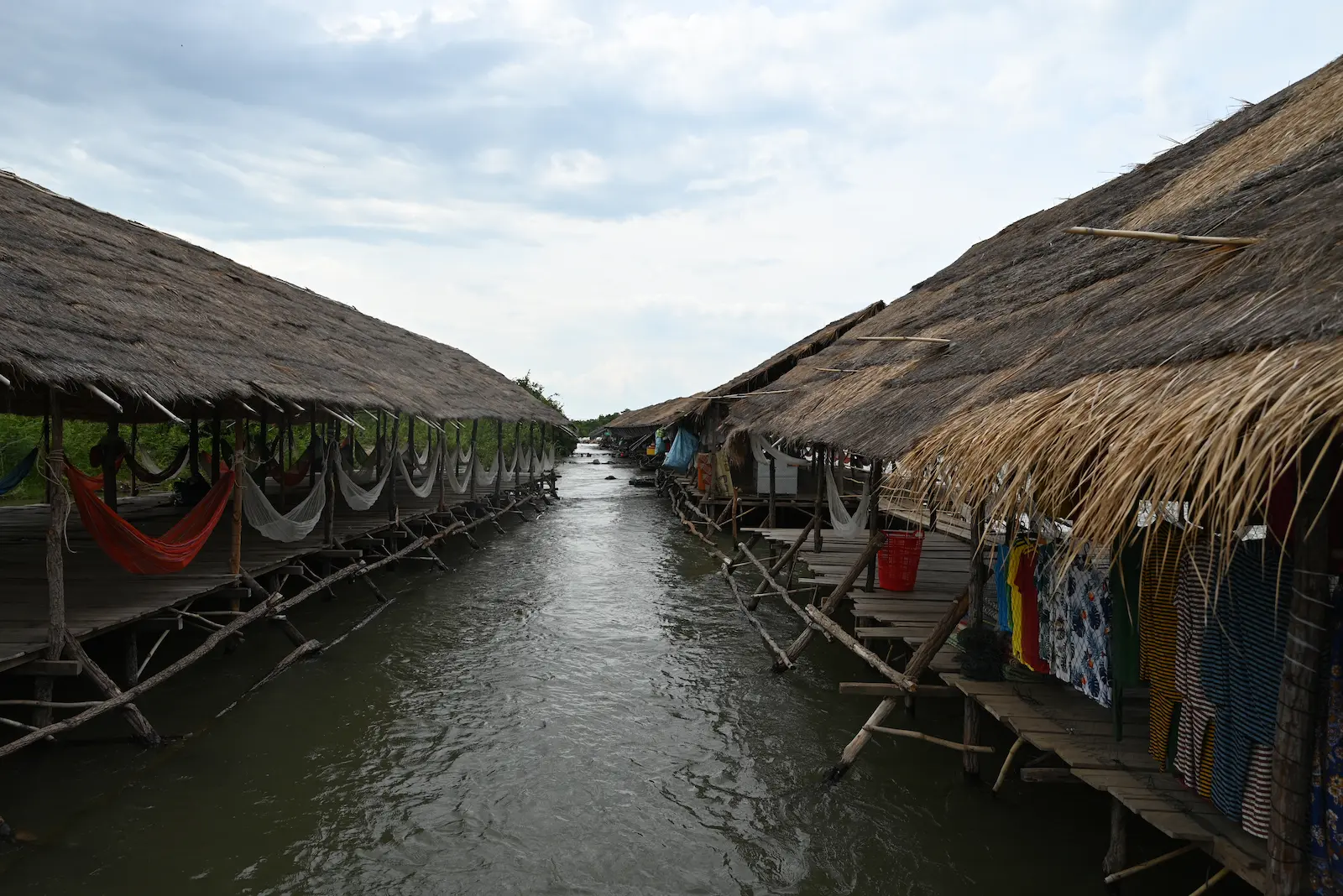Wooden platforms and thatched shelters built over the river at Kampi Rapids. There is one on each side with the river flowing through the middle.