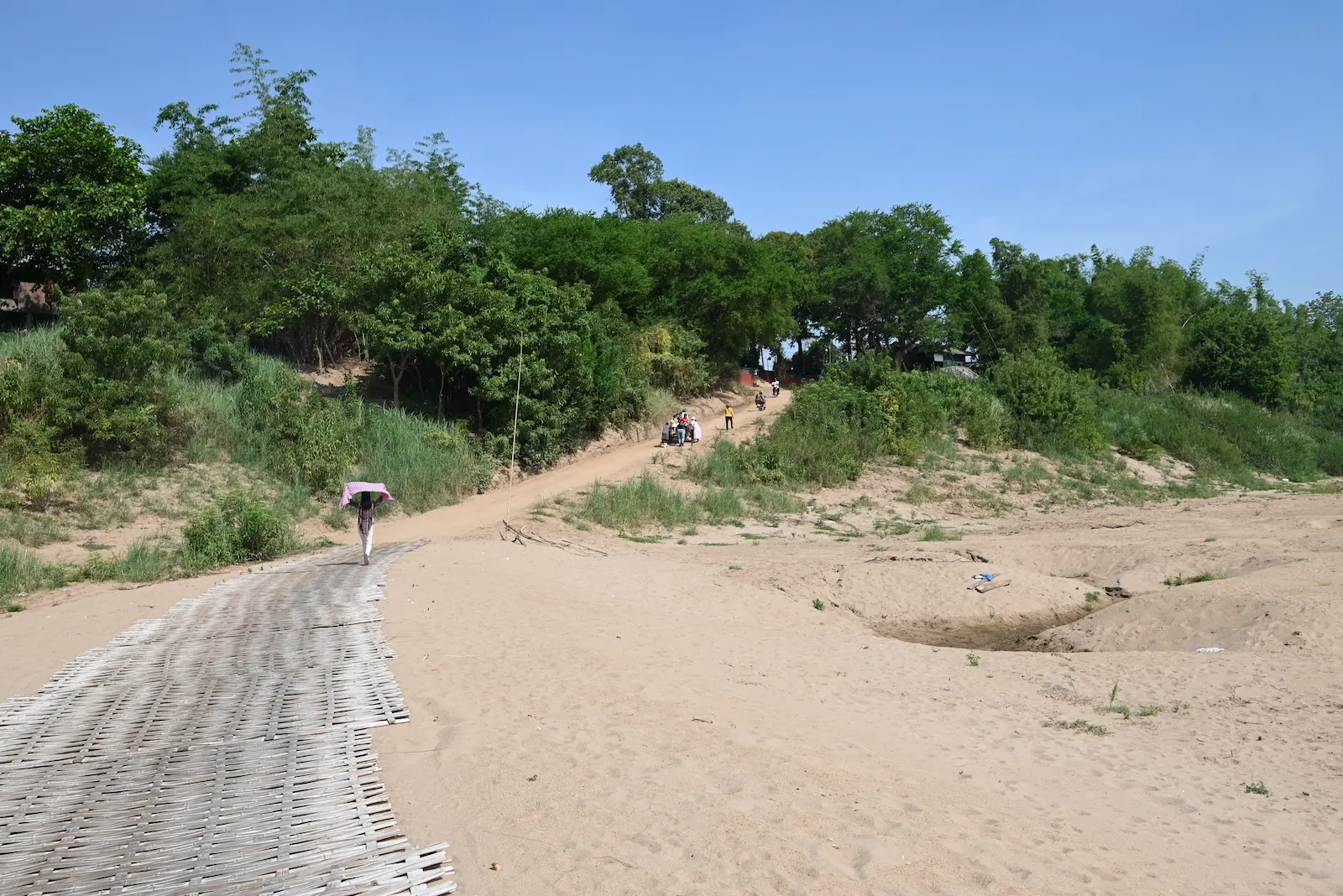 A bamboo path leads to the top of a hill on a beach.