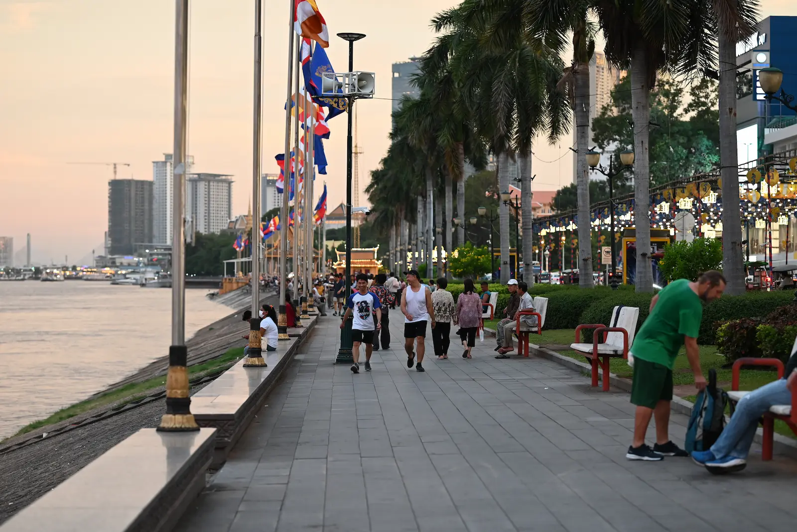 A river promenade with flags and people walking