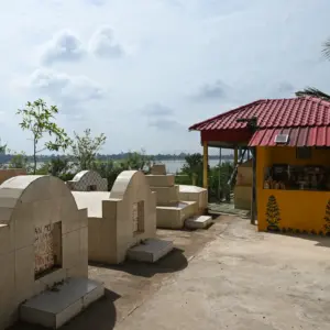 A small yellow building holds a Vietnamese shrine. Next to it is grave stones.
