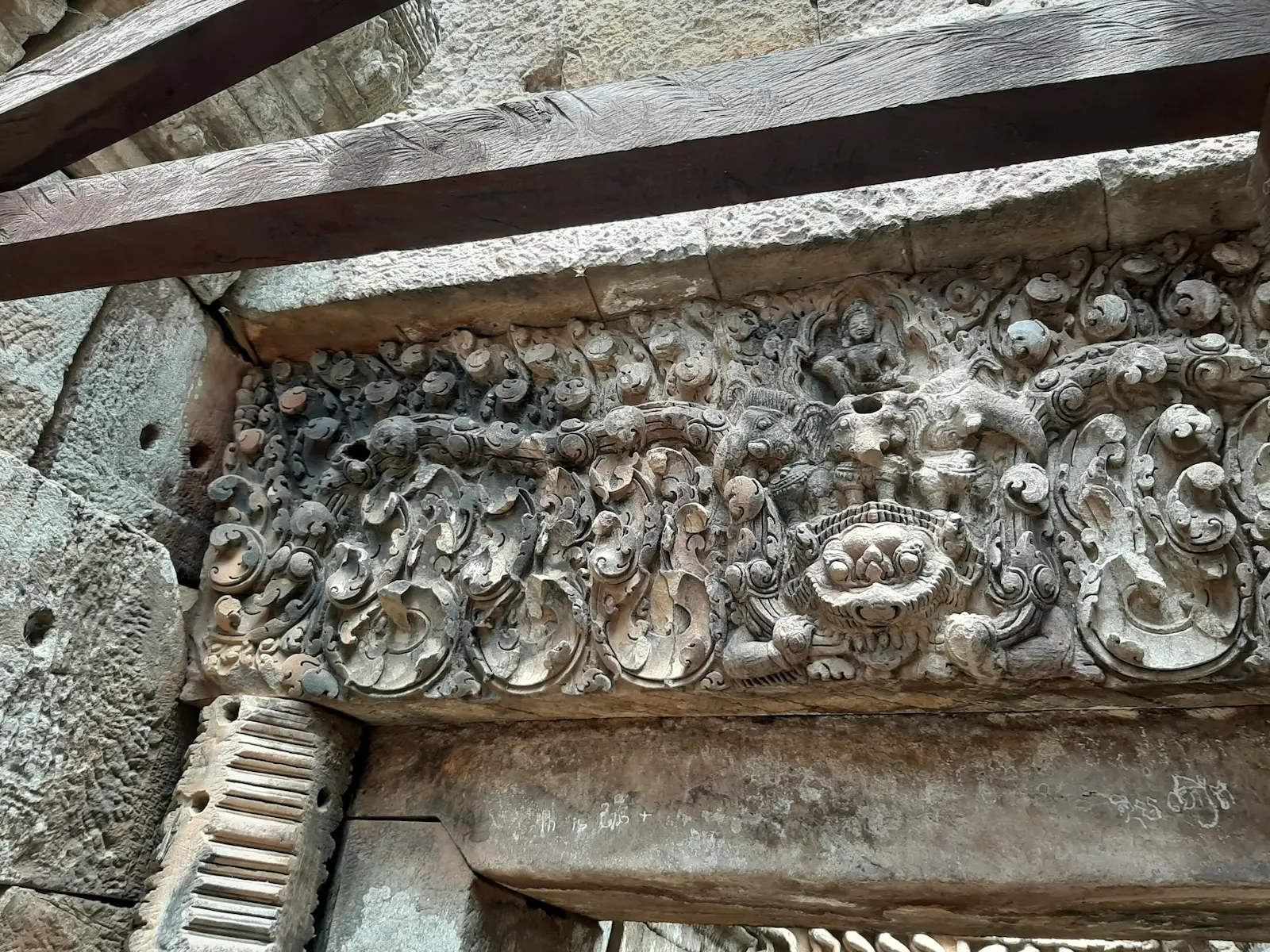Carved sandstone lintel at Ek Phnom Temple in Battambang depicting Kala, a mythical creature from Hindu mythology, eating an elephant.