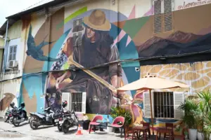 A painted mural of a woman rowing a boat in the Mekong River on the side of a building in Battambang.