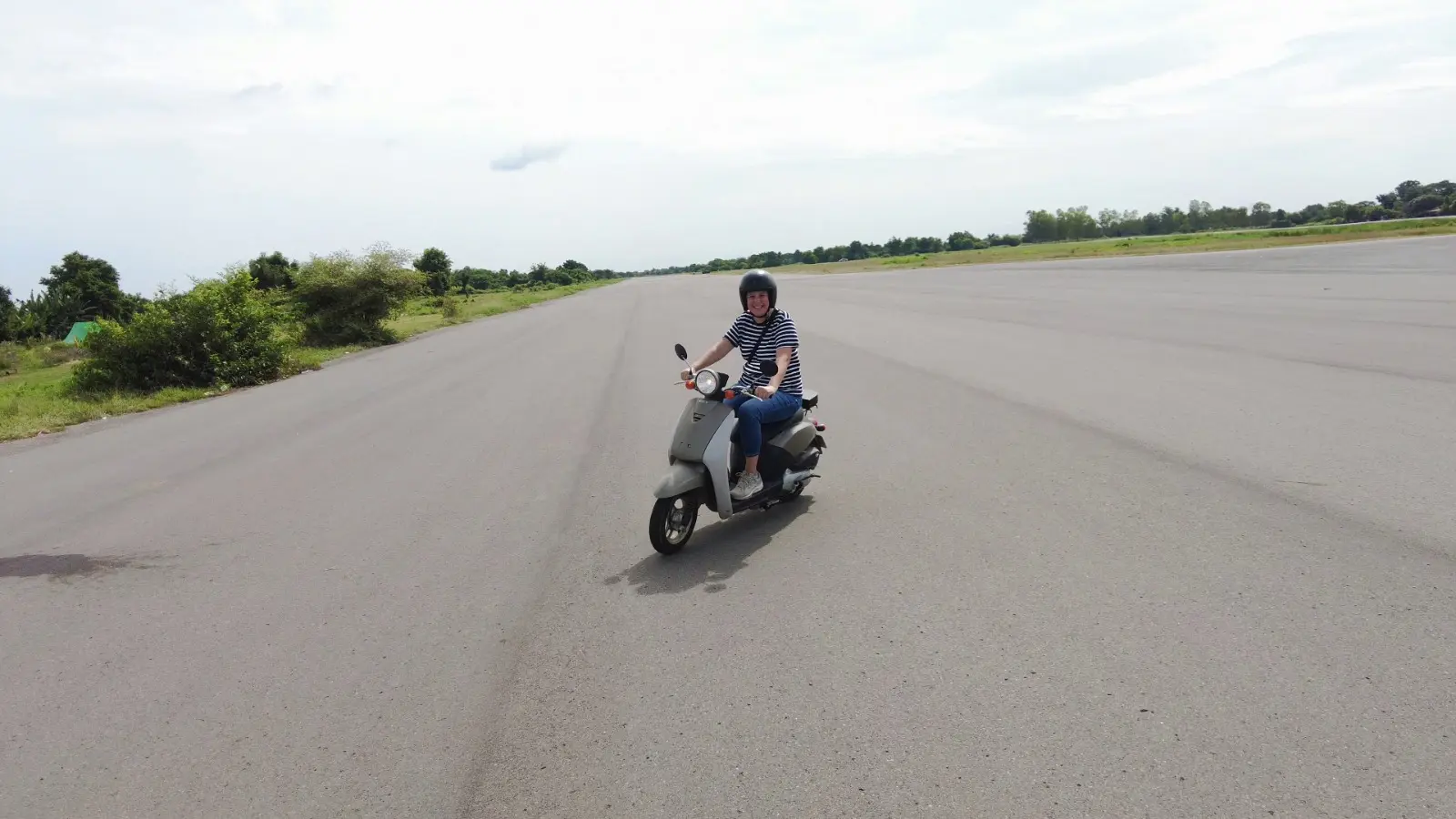 Mel rides a small scooter at Battambang Airport