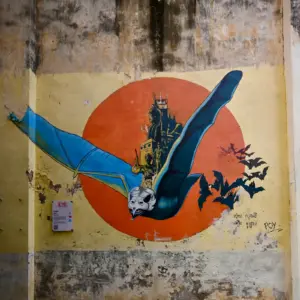 Street art painting of a bat carrying a mountain.