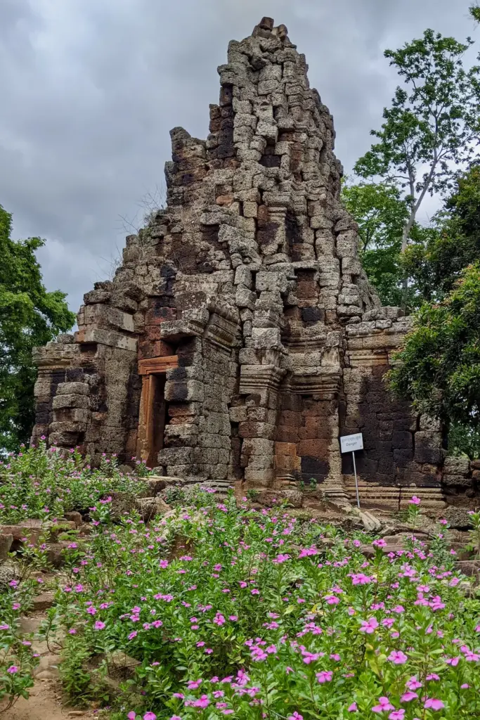 An ancient temple structure stands before a patch of purple wildflowers.